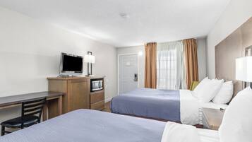 Une chambre d’hôtel avec deux lits, un bureau avec une télévision, un minibar et une porte.