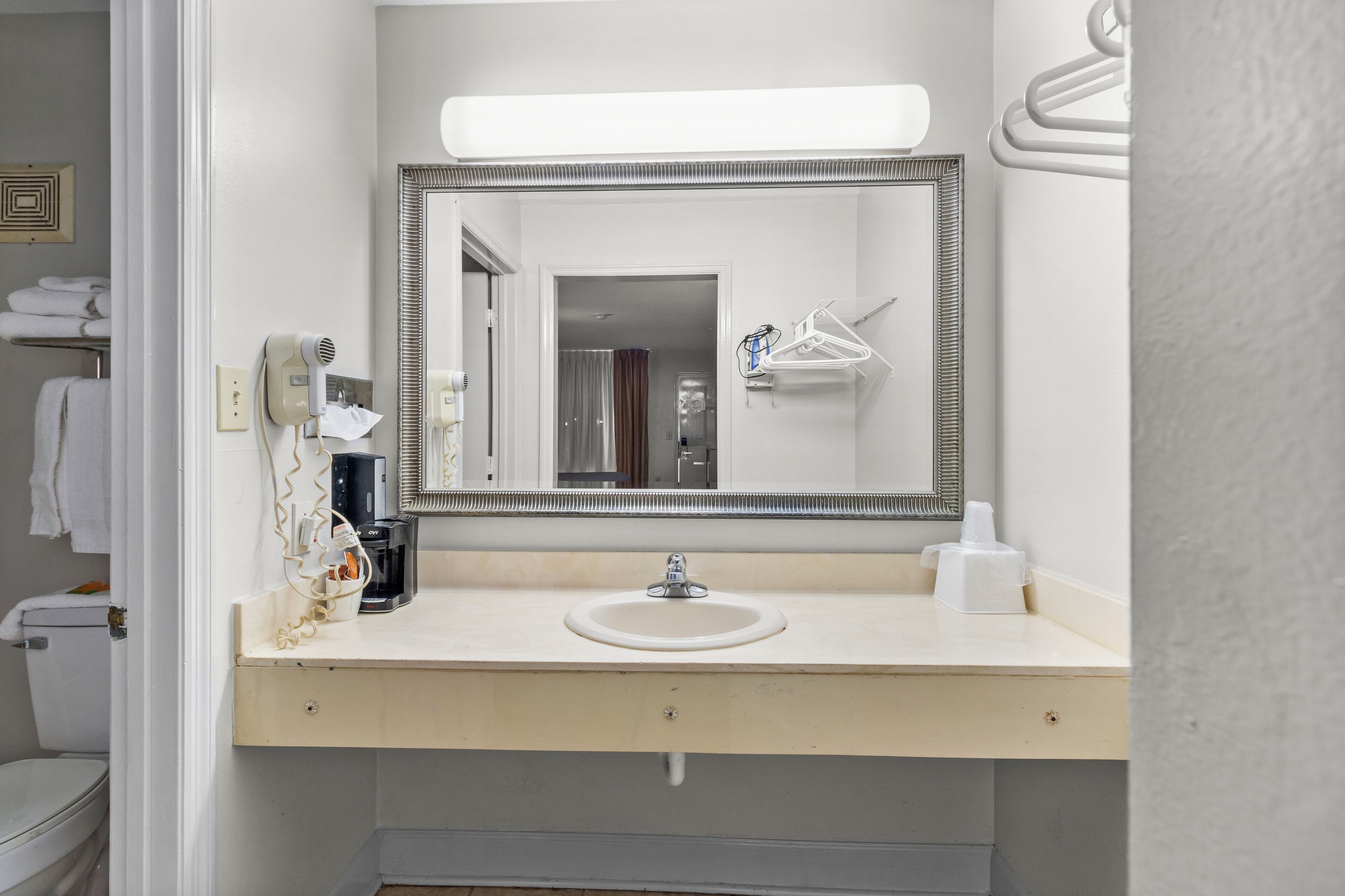 Baño con lavabo, espejo, toallero y secador de pelo.