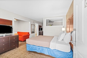 Una habitación de hotel con cama, televisión, escritorio y silla.
