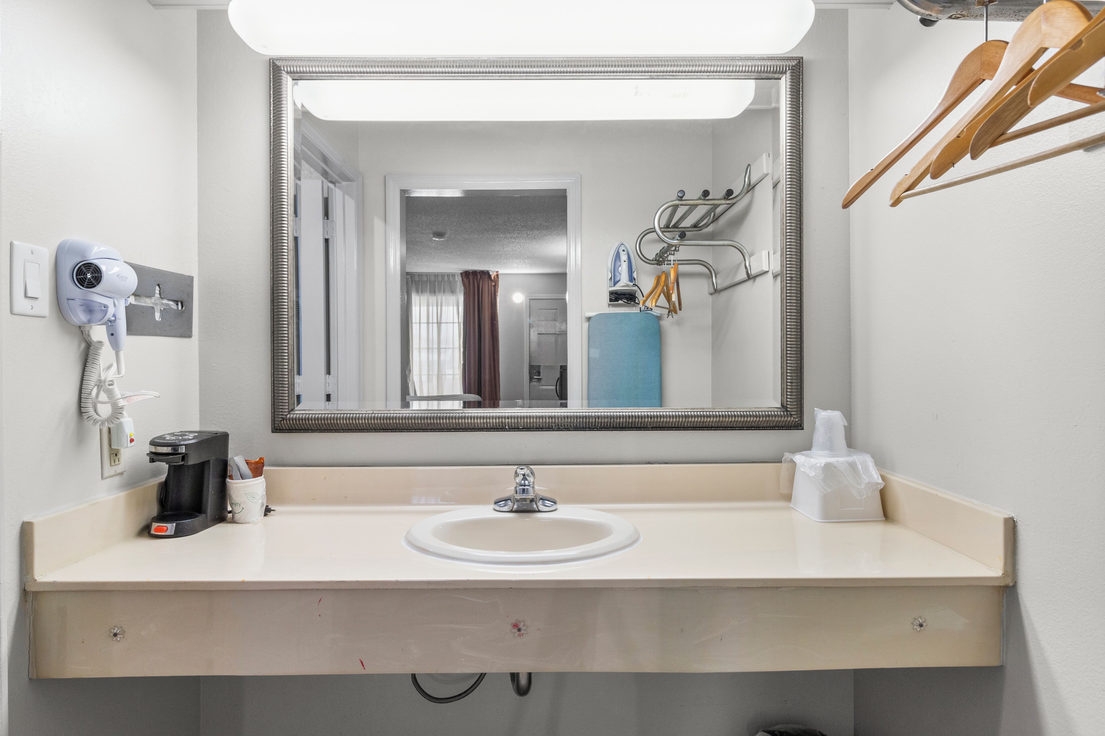 Un baño de hotel con lavamanos, espejo y diferentes artículos de aseo.