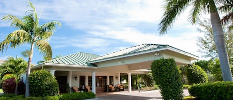 Un hotel con entrada cubierta, palmeras y un camino de ladrillo que conduce a la entrada.