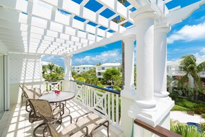 Un balcon avec une balustrade blanche, une table ronde et quatre chaises.