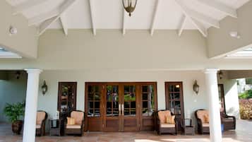 A covered outdoor area with a white ceiling, two doors, and seating arrangements.