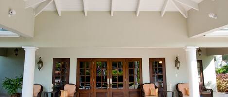 A covered outdoor area with a white ceiling, two doors, and seating arrangements.