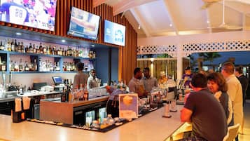 A bar area with multiple TVs, a well-stocked liquor shelf, and a counter with bar tools.