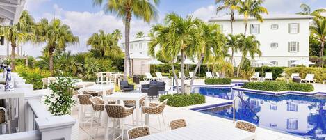 A poolside area with outdoor seating, palm trees, and a swimming pool.