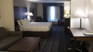 A hotel room with a bed, a sofa, a desk, and a chair. - Crossroads Inn And Suites (Salem)