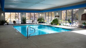 An indoor swimming pool with clear blue water, surrounded by lounge chairs and potted plants. - Crossroads Inn And Suites (Salem)