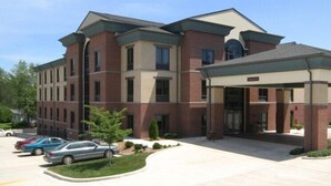 A multi-story hotel with a covered entrance and a parking lot. - Crossroads Inn And Suites (Salem)