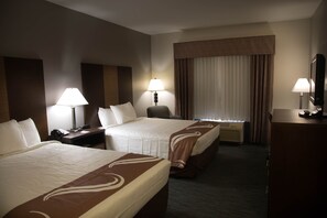 A hotel room with two beds, a desk, a chair, a lamp, a mirror, and an air conditioning unit. - Crossroads Inn And Suites (Salem)
