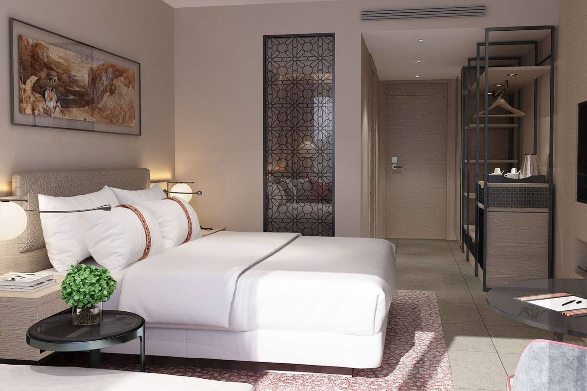 Een moderne hotelkamer met een groot bed, nachtkastjes, een televisie en een badkamer die door een open deur zichtbaar is.