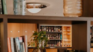 Zona de bar moderna con estantes llenos de botellas de licor, una barra y asientos.