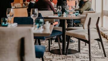 A modern dining area with tables and chairs, a waiter serving a customer, and a patterned floor.