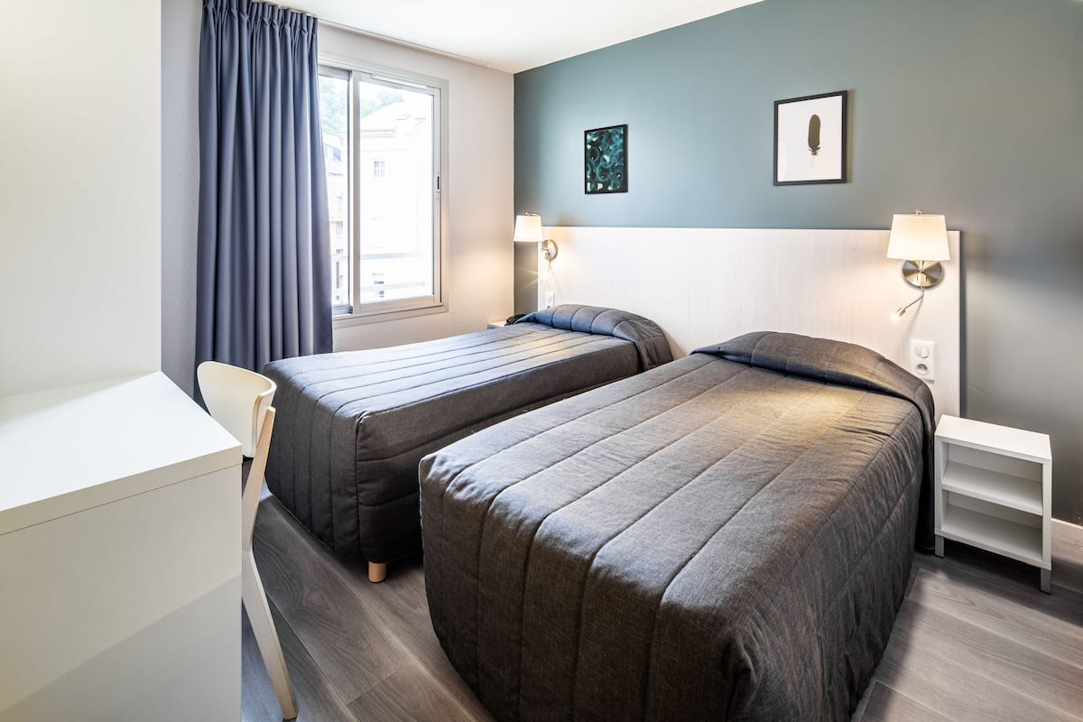 Ein Hotelzimmer mit zwei Betten, einem Schreibtisch und einem Stuhl.