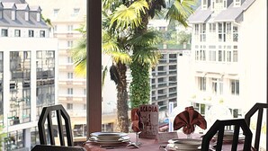 Mesa dispuesta para comer con vista a edificios y una palmera.