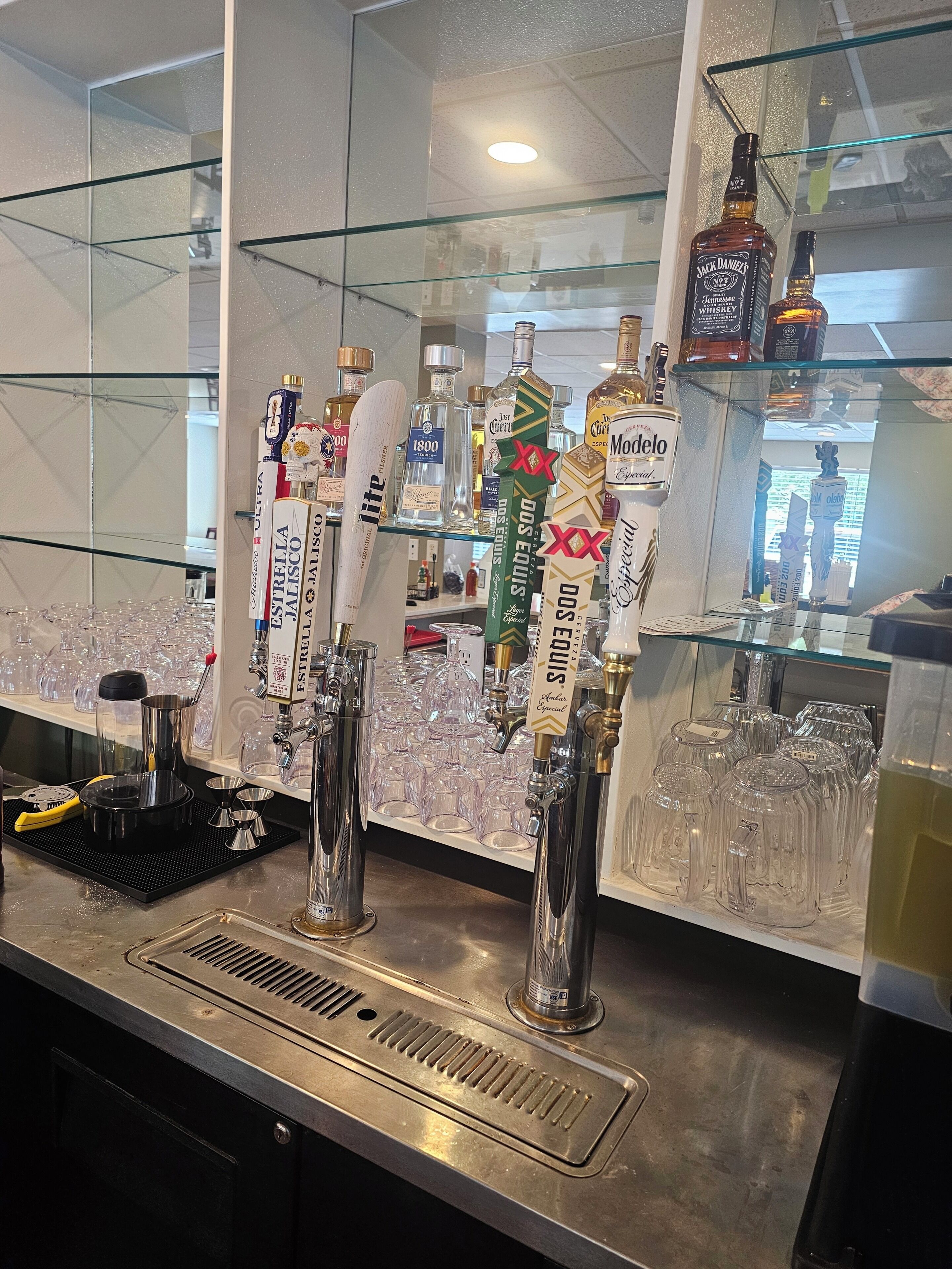 A bar area with multiple taps, glasses, and bottles of alcohol.