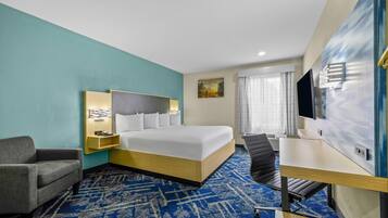 A hotel room with a bed, a desk, a chair, a TV, and a painting on the wall.