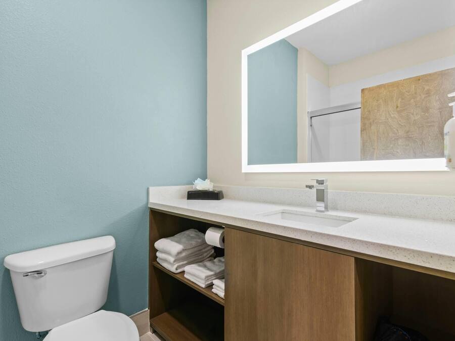 Un baño con inodoro, lavamanos, espejo y espacio para toallas.