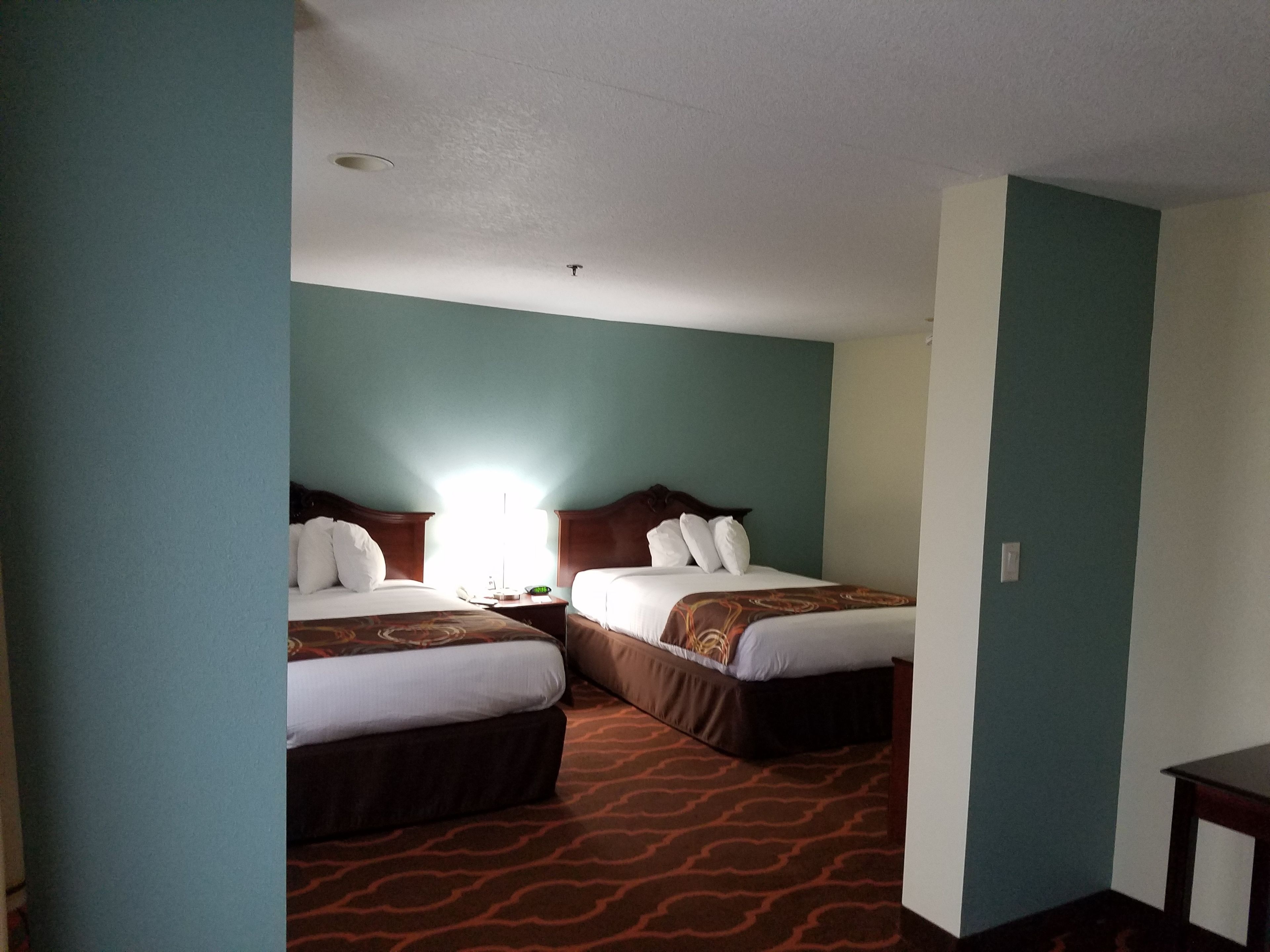 A hotel room with two beds, a nightstand, and a carpeted floor.