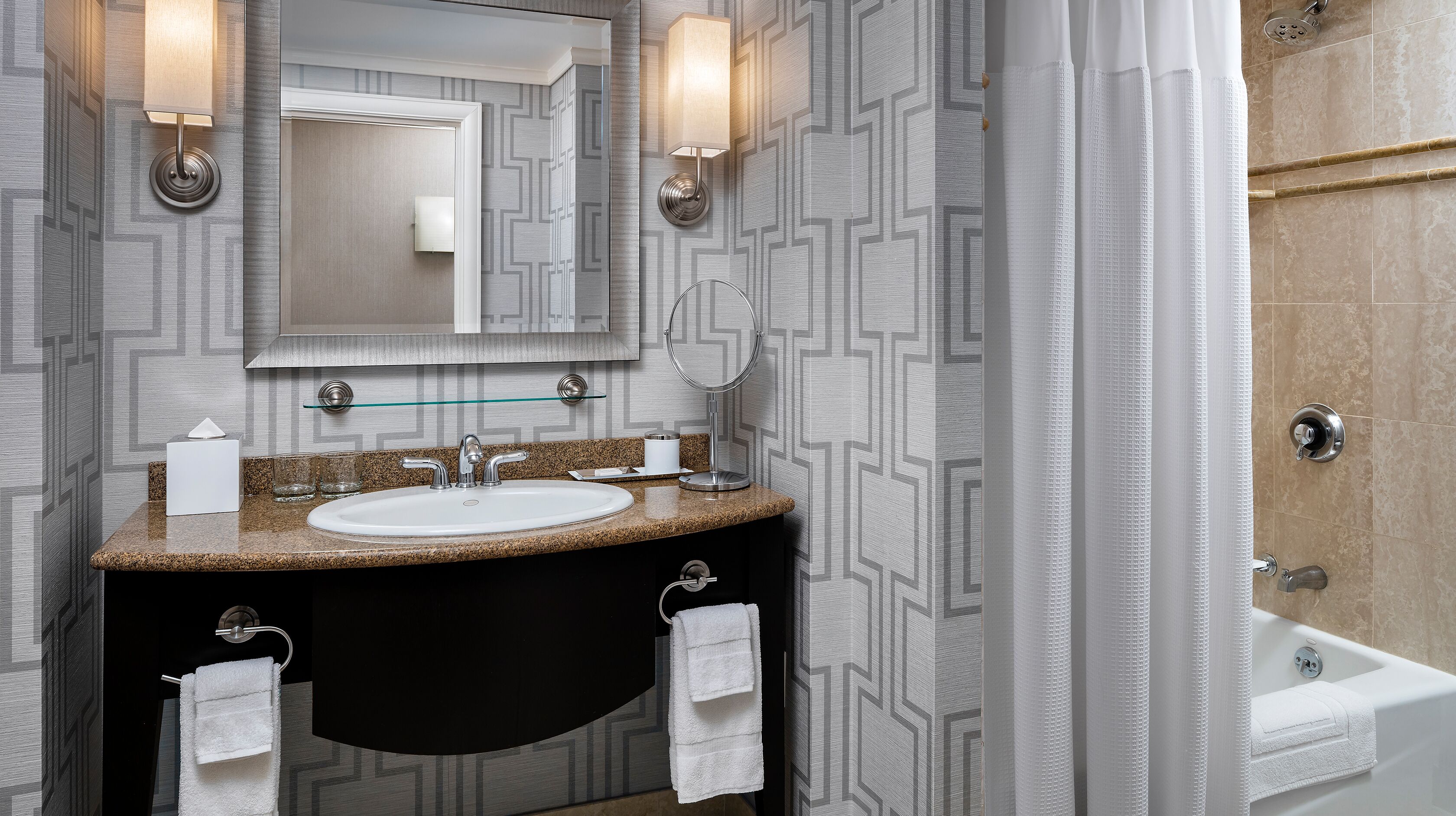 A bathroom with a granite countertop sink, a mirror, and a bathtub.