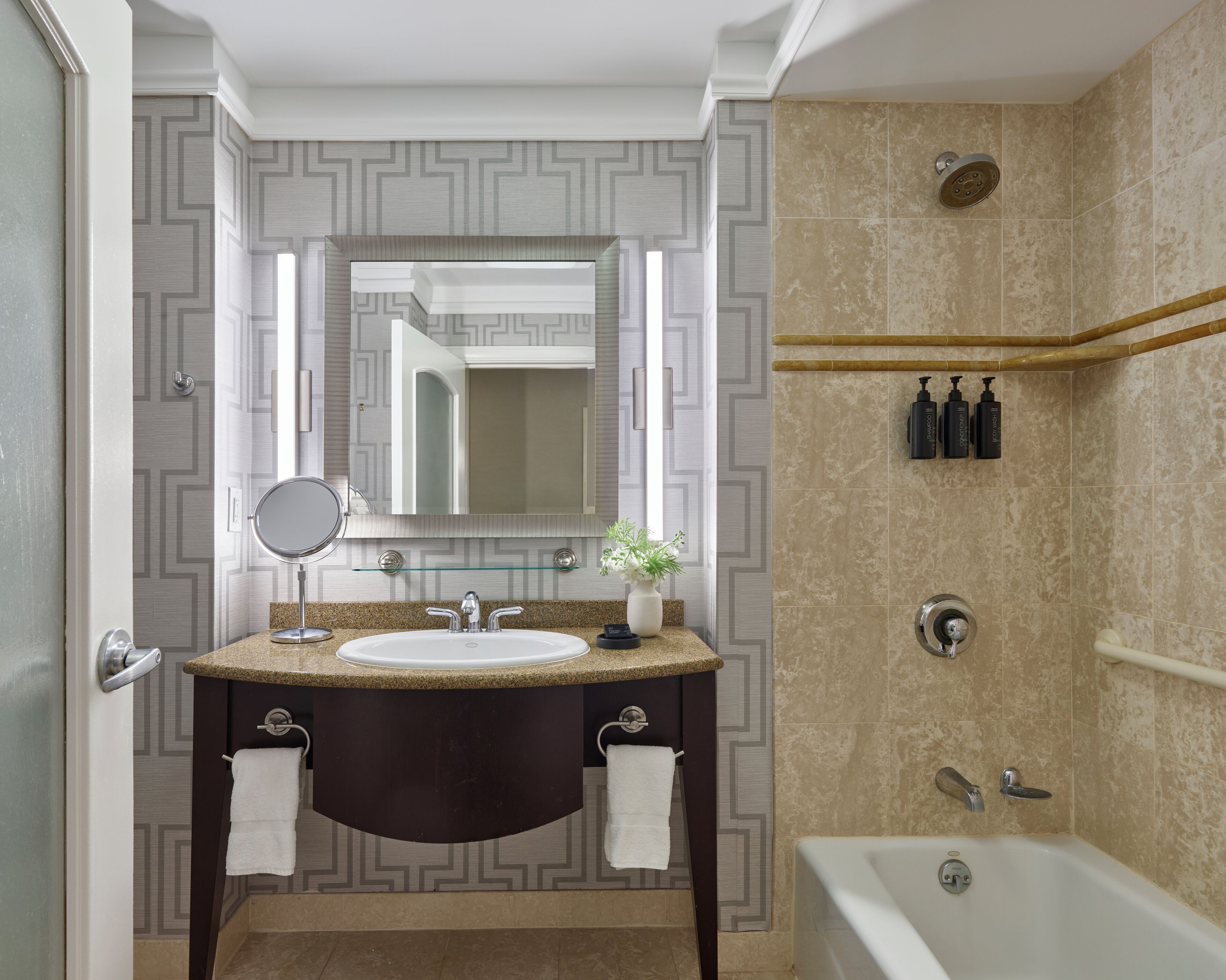 Un baño moderno con tocador, lavabo, espejo y zona de ducha.