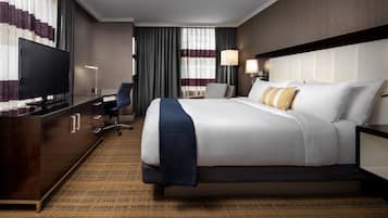 Ein Hotelzimmer mit Bett, Schreibtisch, Fernseher und Stuhl.