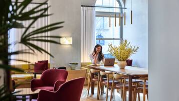 Un comedor moderno con una mesa de madera, sillas rojas y una computadora portátil.