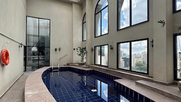 Una piscina al aire libre, sillones reclinables de piscina