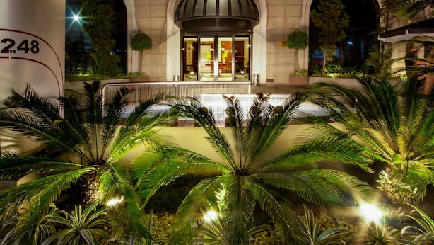 A building with a large arched entrance, a number '248' on the left, and a well-lit interior with visible furniture. - Clarion Hotel Faria Lima (São Paulo)