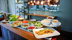 A buffet with various dishes and a kitchen area in the background. - Clarion Hotel Faria Lima (São Paulo)