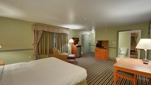 A hotel room with two beds, a desk, a chair, a television, a dresser, and a door leading to a bathroom. - Colonial Motel (Brattleboro)