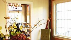 A dining table with a vase of flowers, a chair, and a window with a view. - Colonial Motel (Brattleboro)