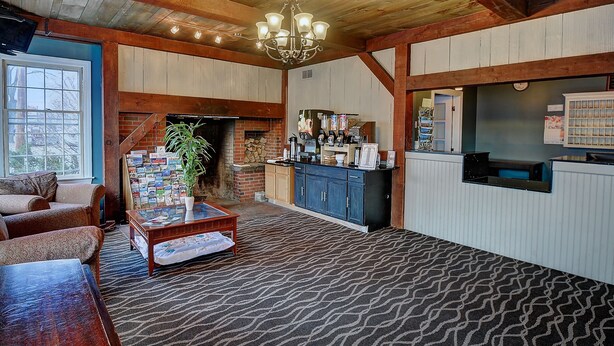 A cozy living room with a fireplace, a coffee station, and a view of the outside. - Colonial Motel (Brattleboro)