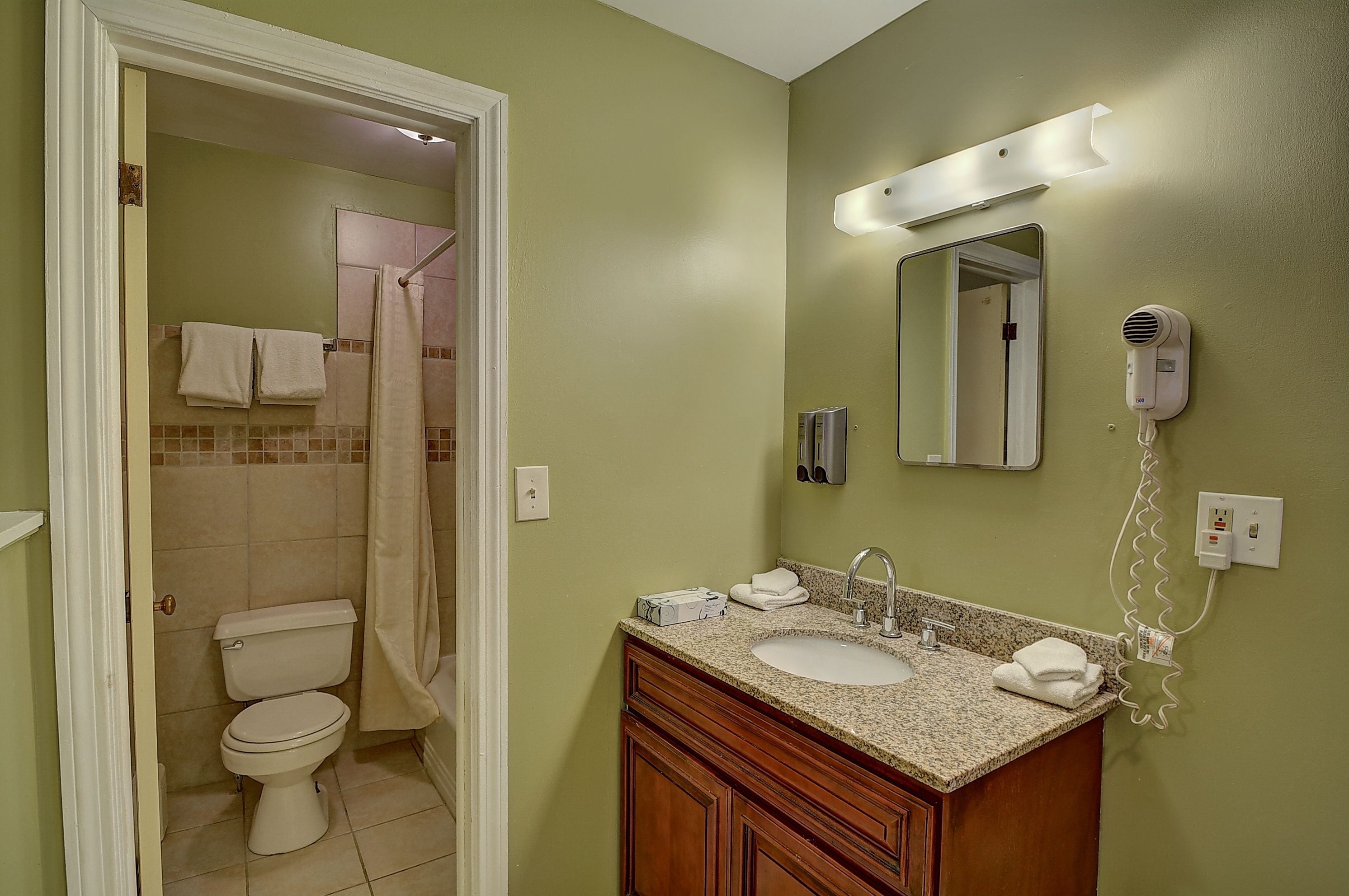 A bathroom with a toilet, sink, and shower area.