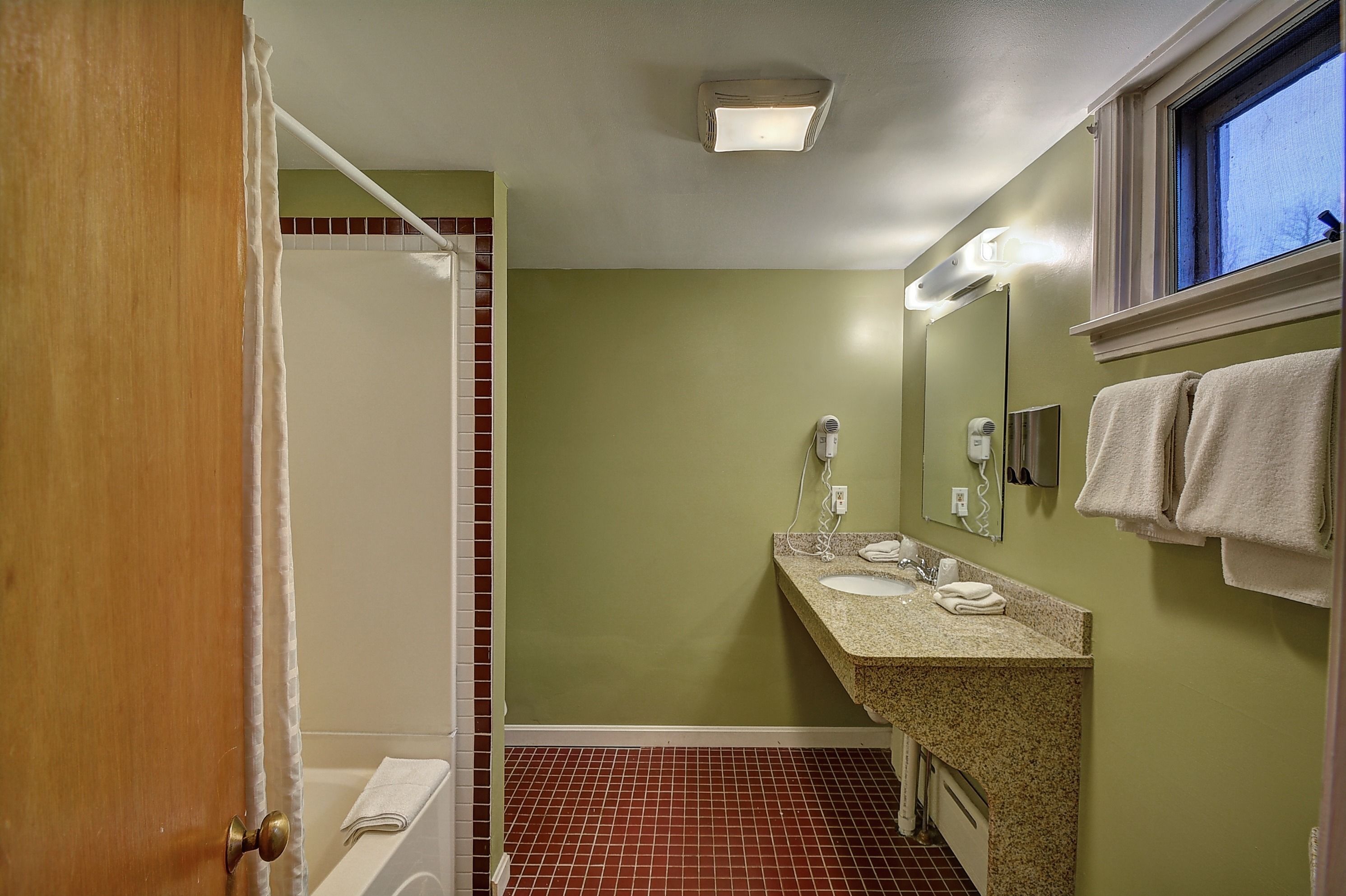 Un baño con ducha, dos lavamanos, un espejo y una ventana.