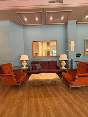 A room with a sofa, two armchairs, a coffee table, a mirror, and a sign indicating a breakfast room. - Mokinba Hotels King (Milan)