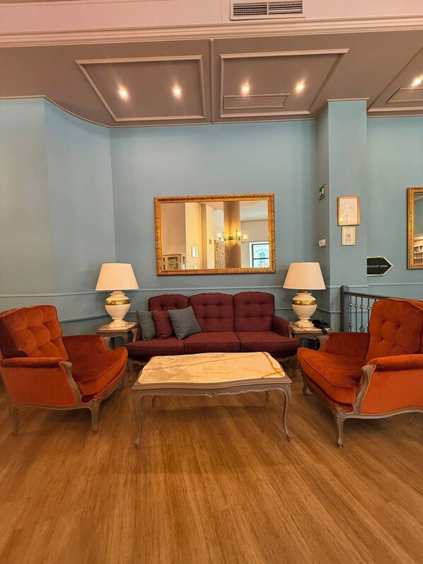A room with a sofa, two armchairs, a coffee table, a mirror, and a sign indicating a breakfast room.