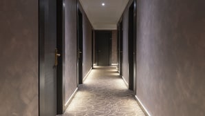 A long, narrow hallway with dark walls and a patterned carpet.