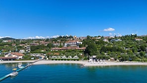 A coastal town with a marina, beach, and hillside buildings. - Riva del Sole (Moniga del Garda)