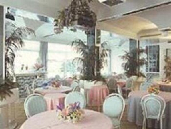 A room with round tables, white chairs, and large windows.
