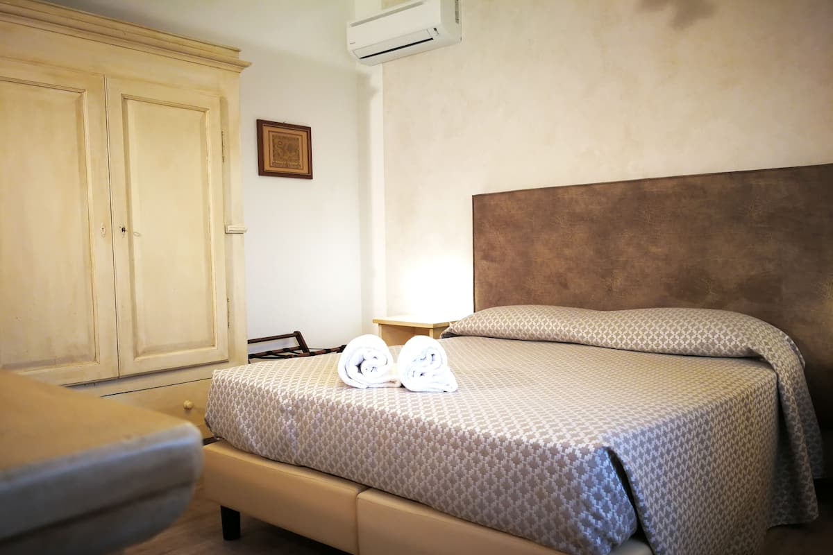 A hotel room with a bed, a wardrobe, and an air conditioning unit.