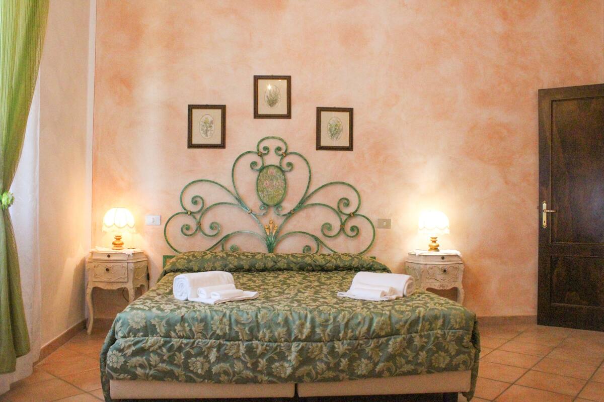 A neatly made bed with a floral bedspread, two bedside tables with lamps, and a door to the right.