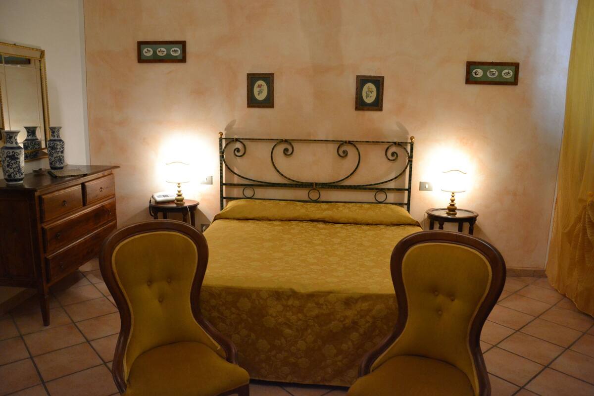 A bedroom with a bed, two nightstands, a dresser, and two chairs.