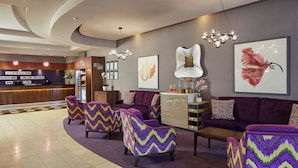 Un hall d’entrée avec un comptoir de réception, des canapés violets et des fauteuils à motifs chevrons.