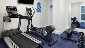 Une salle de sport équipée de tapis de course, d’un vélo d’appartement et d’un banc de musculation.