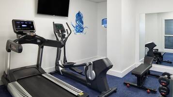 Un gimnasio con cintas de correr, una bicicleta estática y un banco.
