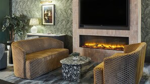 Un salon moderne doté d’une cheminée, de sièges confortables et d’un téléviseur à écran plat.