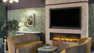 A modern living room with a fireplace, comfortable seating, and a flat-screen TV.