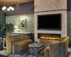 Un salon moderne doté d’une cheminée, de sièges confortables et d’un téléviseur à écran plat.