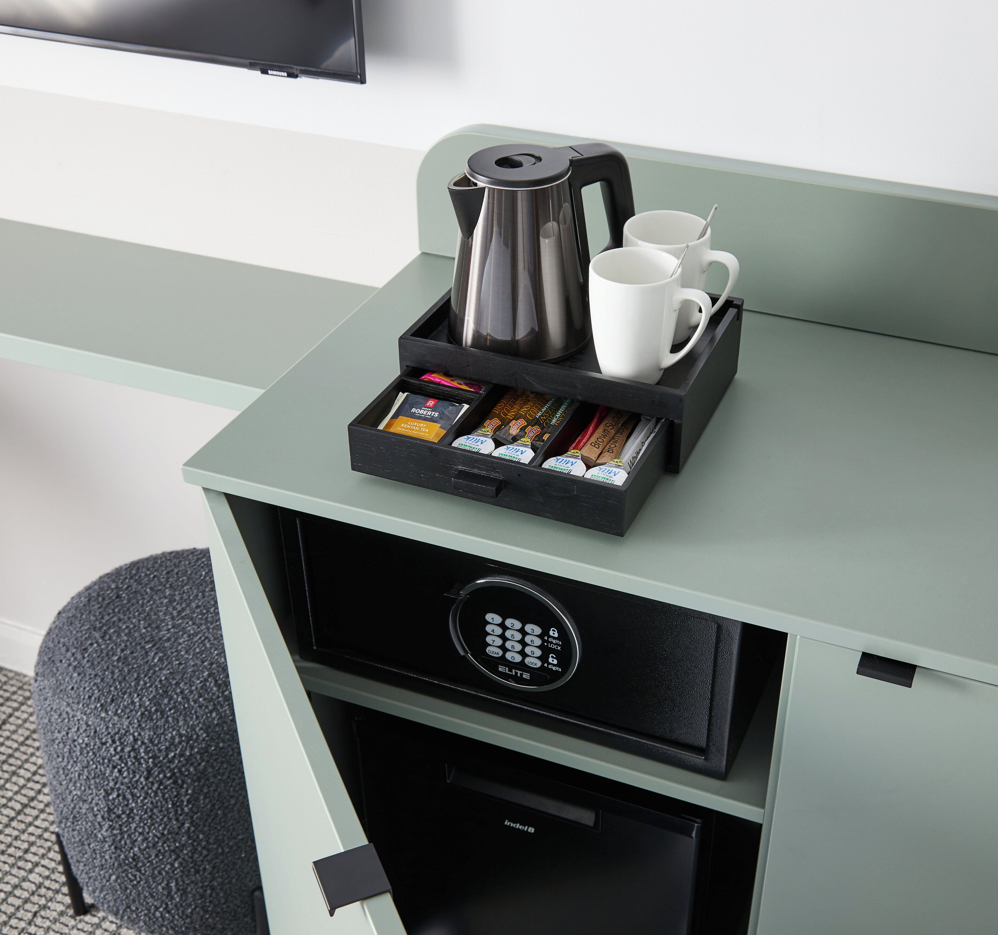 Un mini bar amb una cafetera, una tassa i diferents aperitius.
